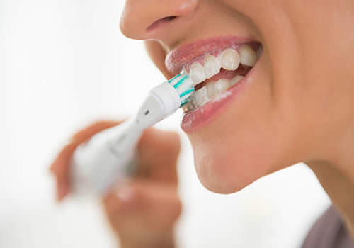 Woman brushing her teeth with electric toothbrush