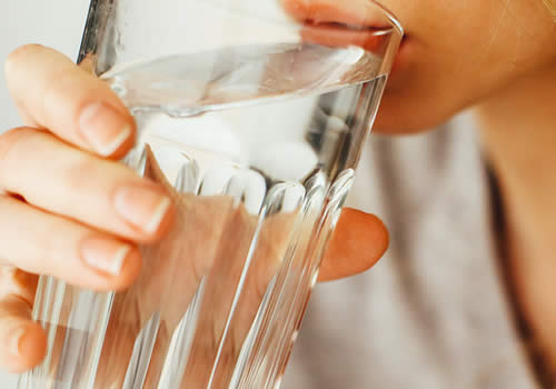 Person drinking a glass of water to stay hydrated